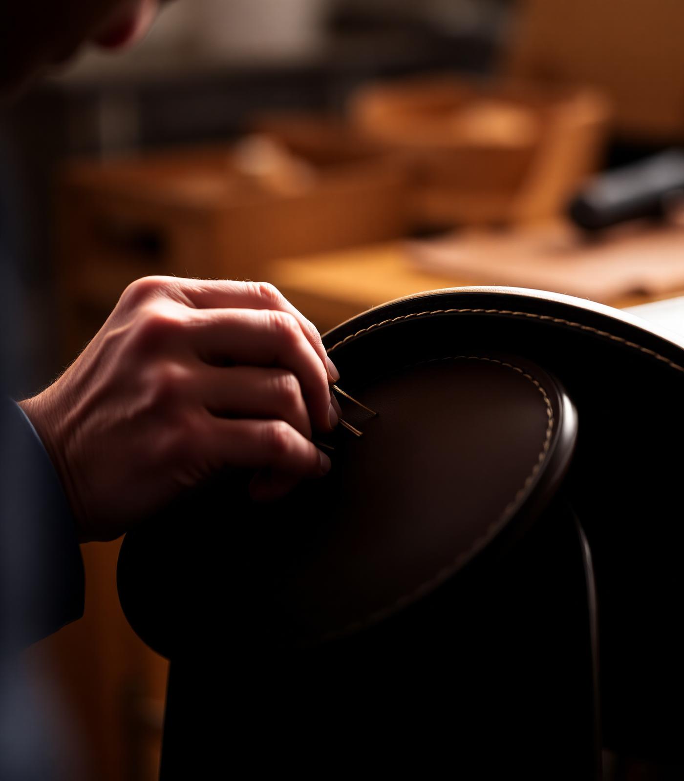 Artisan hand-stitching a leather saddle